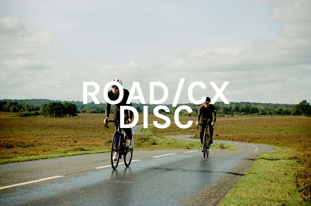 Two road cyclists riding up a hill with Road/CX DISC title across image